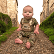 Load image into Gallery viewer, Baby in Multicam Tactical Uniform with flak jacket print and US flag, sitting on stone path surrounded by greenery.