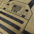 Load image into Gallery viewer, Close-up of screen-printed flak jacket design on FBI Baby Flak Jacket Baby Bodysuit with American flag detail.