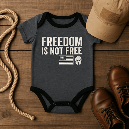 Graphite gray Baby bodysuit with 'Freedom Is Not Free' print and American flag on the sleeve, styled with boots and hat.