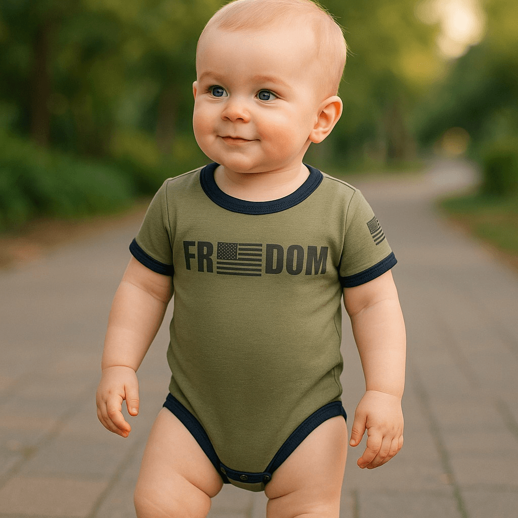 Baby in olive green Freedom Flag bodysuit with American flag design walking on a pathway outdoors.