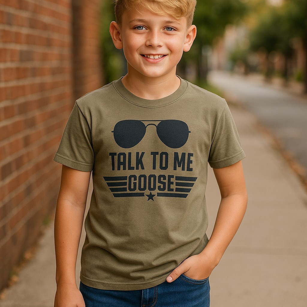Boy wearing a Talk To Me Goose shirt in OD Green, inspired by Top Gun, with aviator sunglasses design.