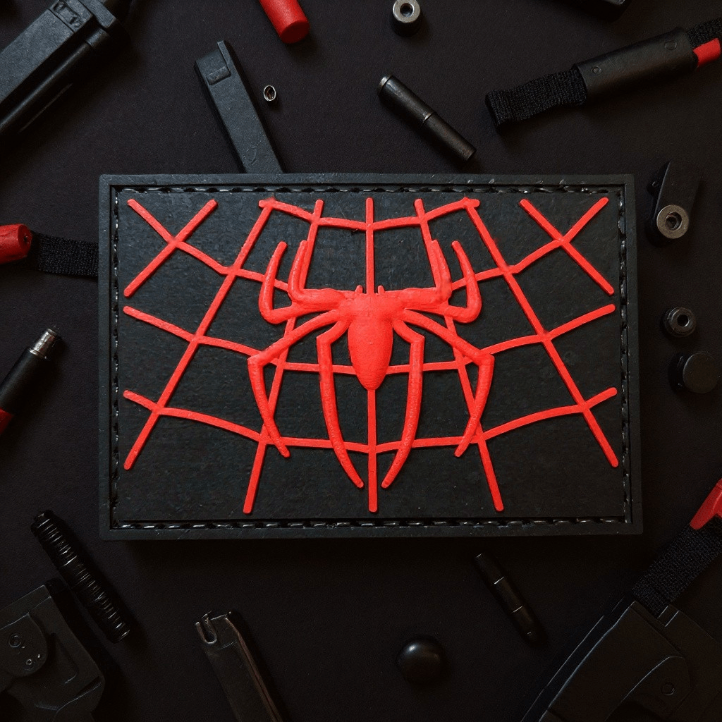 Spiderman web chest logo patch on a black background, featuring a red spider design and web pattern.
