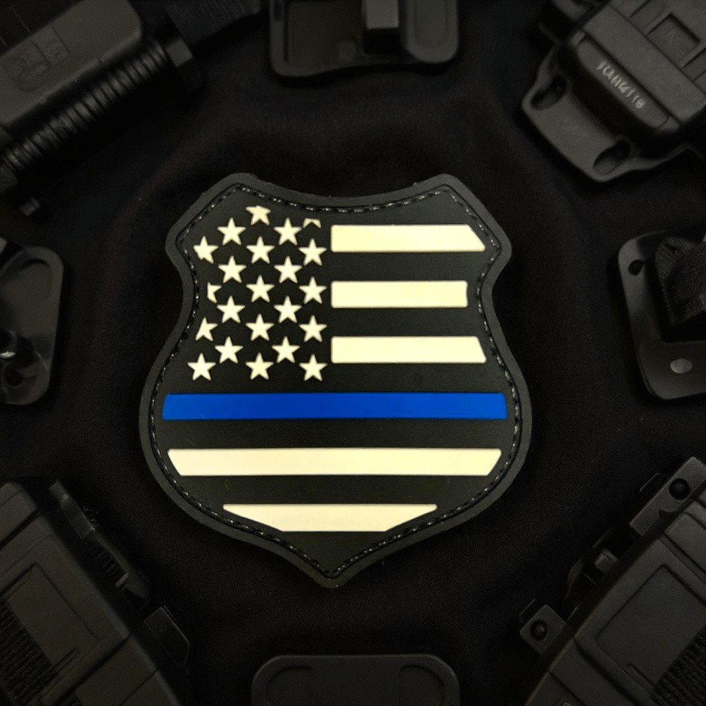 Thin Blue Line Shield Patch featuring a black PVC design with white stars and bars and a blue line.
