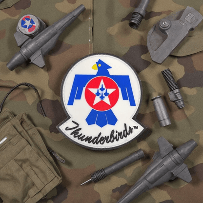 Patch Thunderbirds PVC on camouflage fabric with military accessories, perfect for adding to your gear.