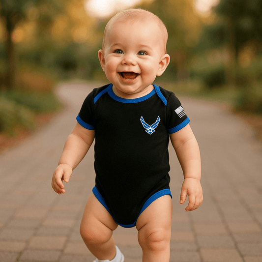Baby wearing a Trooper Licensed Air Force bodysuit with blue trim and smiling outdoors.