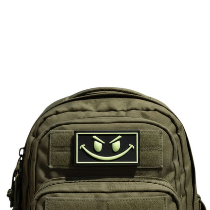 Trooper Clothing black PVC patch with glow-in-the-dark yellow smiley face and border. Hook-and-loop backing.